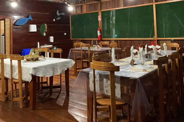 Dining area with wooden tables set for meals at Amazon Mamori Lodge, offering authentic jungle culinary experience.