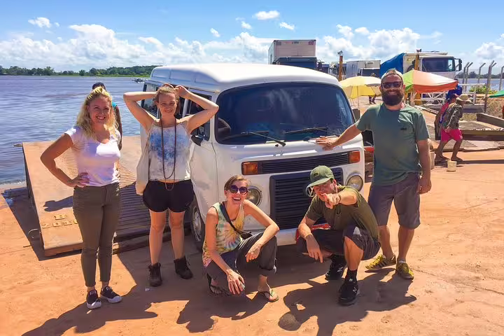 Group of travelers posing by a vintage van at the start of their Amazon jungle adventure tour.
