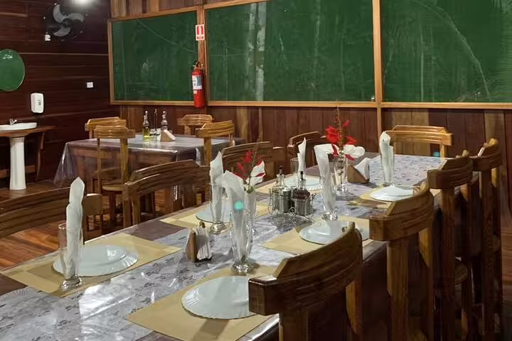 Dining area set with wooden tables and chairs, ready for guests at Amazon Mamori Lodge.
