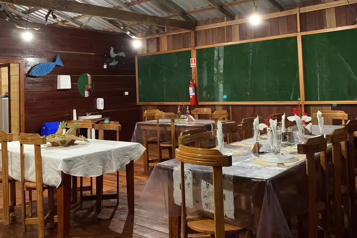 Charming dining area at Amazon Mamori Lodge with wooden furniture, table settings, and green chalkboard backdrop.
