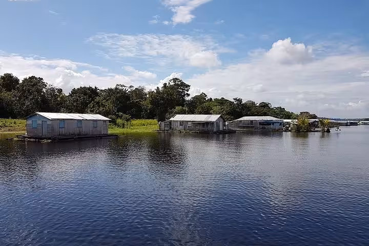 Amazon River floating houses on calm water, scenic stop on stand up paddling tour through rainforest