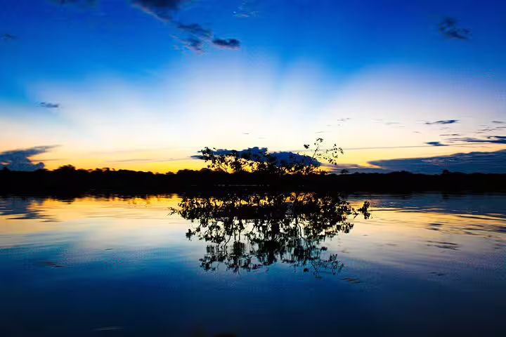 Serene Amazon River sunset with silhouette of vegetation reflecting on water during the Amazon Jungle Adventure tour.