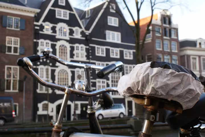 Explore Amsterdam's scenic streets with a bike rental, featuring classic Dutch architecture in the vibrant city backdrop.