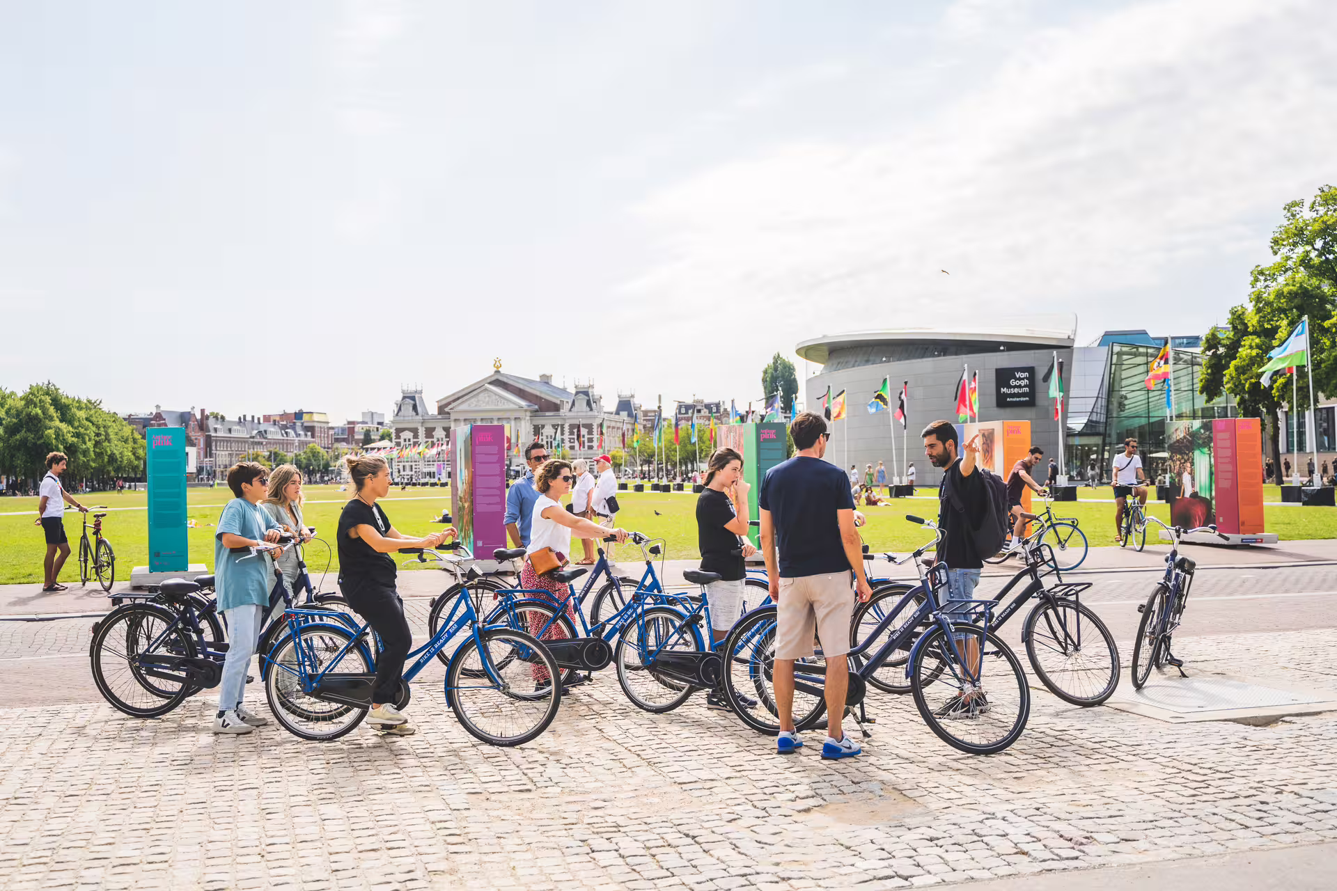 Cyclists gather near the Van Gogh Museum in Amsterdam, preparing for a scenic bike tour and canal cruise adventure.