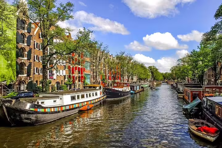 Amsterdam canal houses and houseboats along a sunny waterway, ideal for a self-guided GPS audio tour