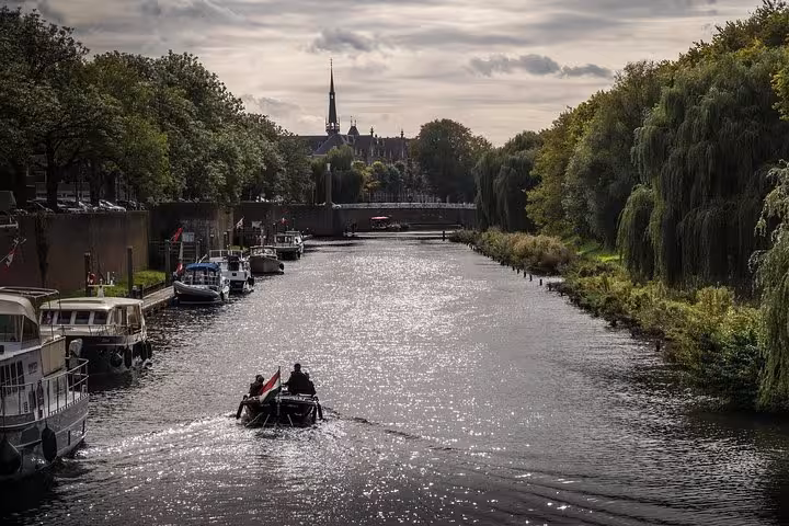 Amsterdam canal with boats and tree-lined banks, ideal backdrop for Schiphol Airport to Den Bosch transfer