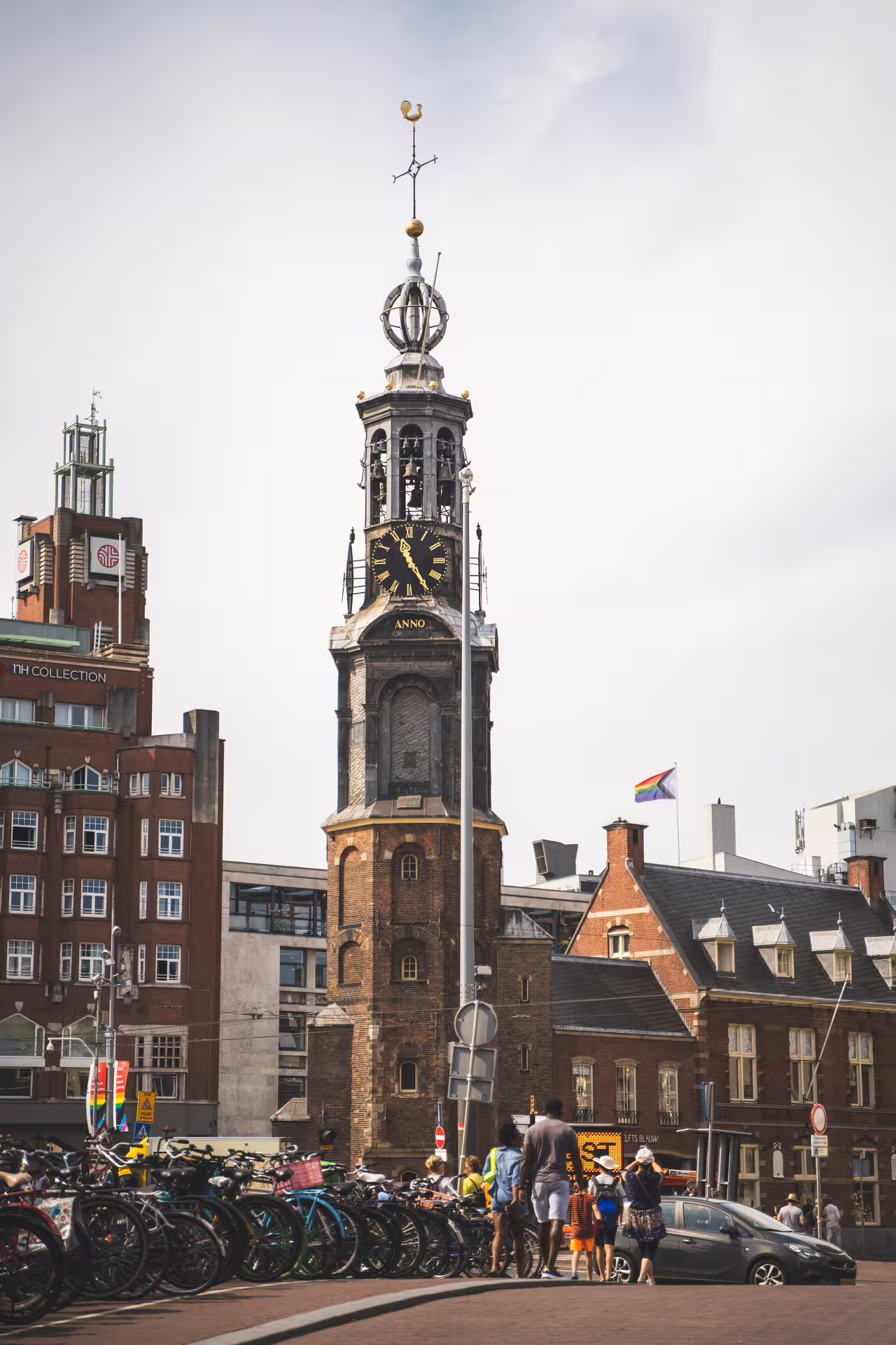 Historic Amsterdam clock tower and bustling street scene captured on a private walking tour, showcasing Dutch architecture and culture.