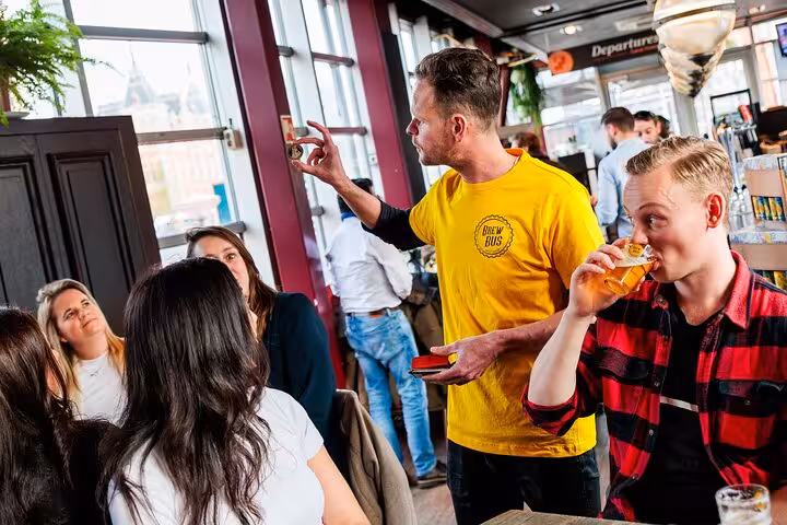 Brew Bus guide explaining Amsterdam craft beer tasting as guest sips lager with cheese and sausage snacks