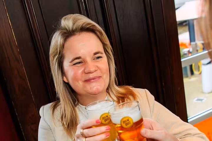 Traveler sipping Dutch craft beer at an Amsterdam tasting stop with paired cheese and sausage on guided tour
