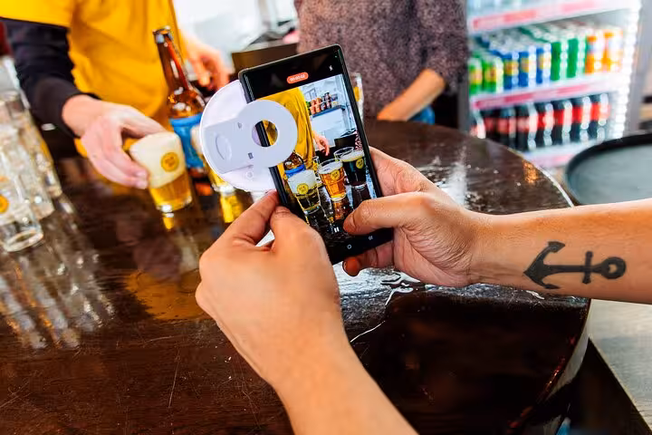 Guest photographing beer tasting at Amsterdam craft brewery bar during guided tour with cheese and sausage pairing