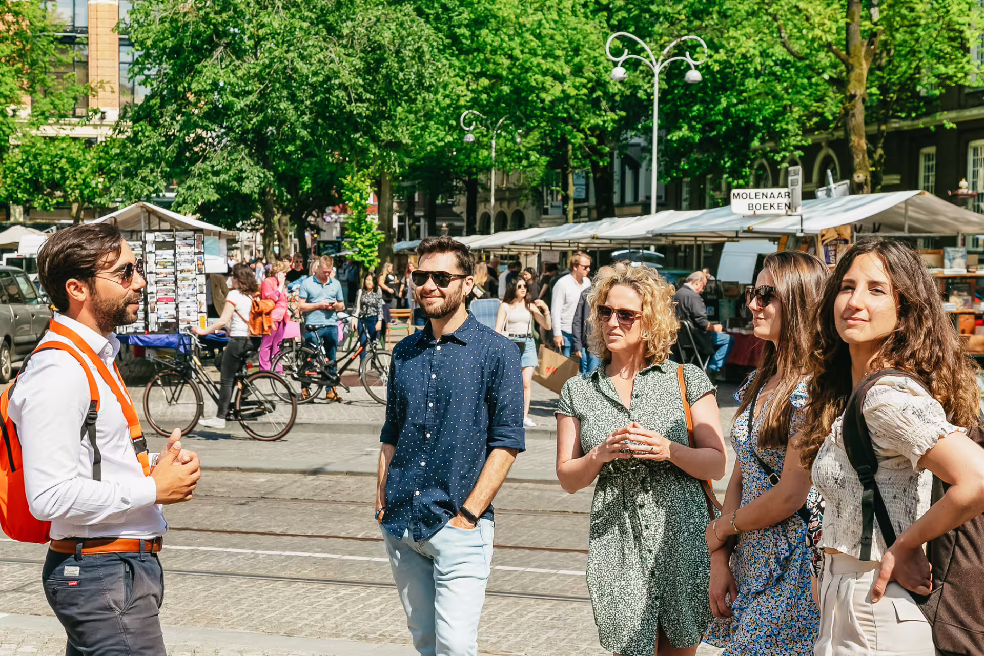 Tour guide leading a group through Amsterdam's historical sites on a sunny day, highlighting hidden secrets and local culture.