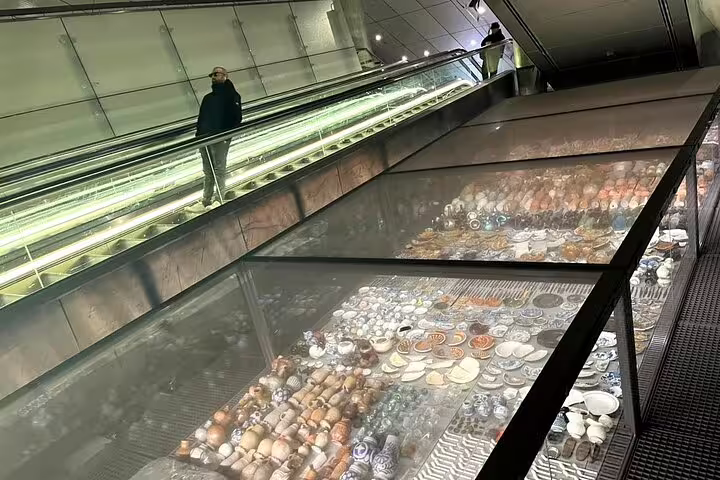 Escalator beside glass display of ceramics at Amsterdam metro, seen on Your Own Amsterdam: The Art Underground tour