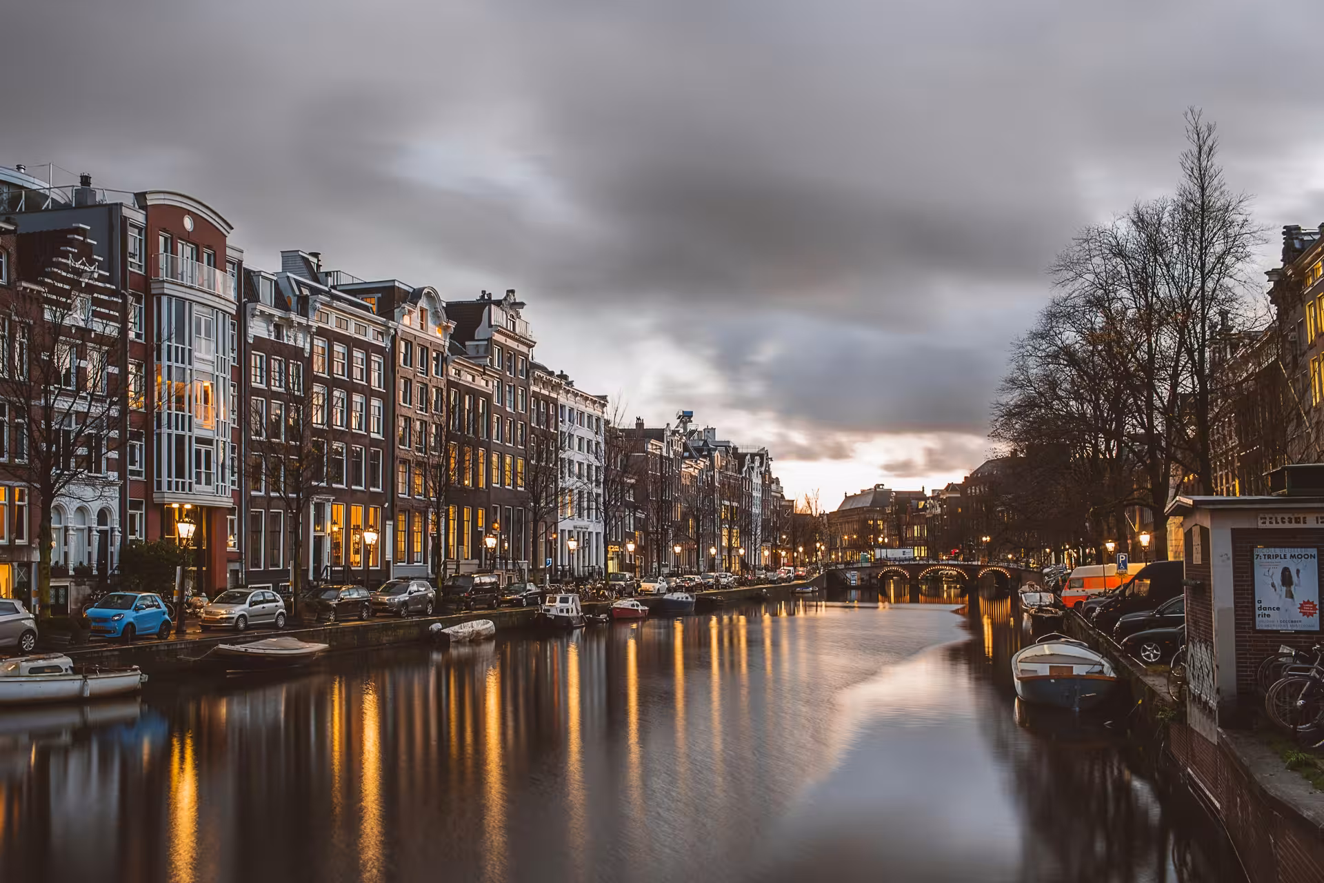 Amsterdam private layover tour along iconic canal at dusk with canal houses, bridges, boats and reflections