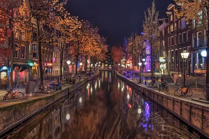 Amsterdam canal at night with city lights and bikes, perfect for Amsterdam to Schiphol private airport transfer