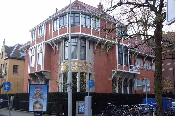 Amsterdam School style corner building with balconies and murals, seen on self-guided GPS audio architecture walk