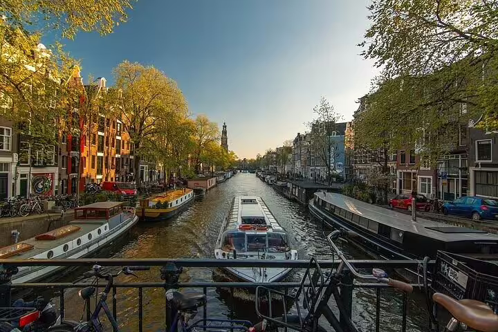 Scenic Amsterdam canal view during winter sunset with boats, historic buildings, and tree-lined streets perfect for a winter walk.