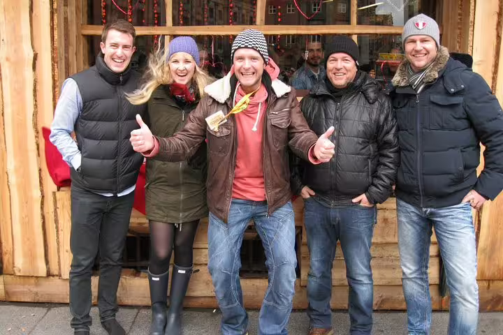 Group enjoying a lively Amsterdam winter walk, dressed warmly in jackets and hats, smiling in front of a cozy wooden cafe.