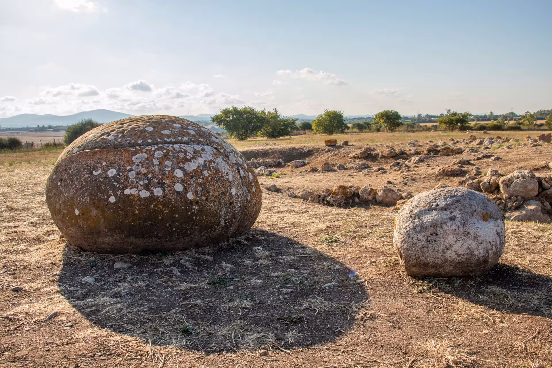 Ancient stone spheres at Su Crucifissu Mannu, Porto Torres, Sardinia, under clear skies.