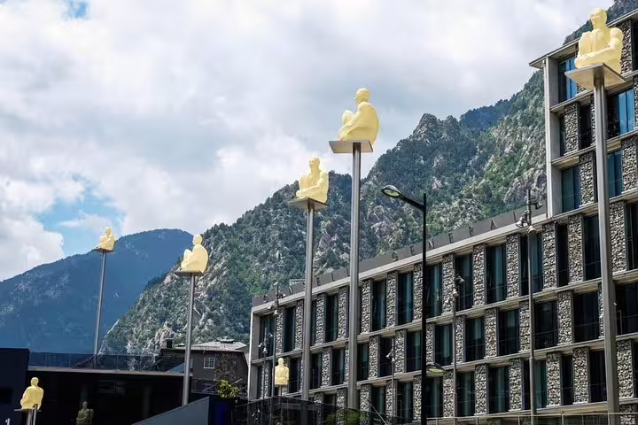 View of modern sculptures on poles against mountainous backdrop in Andorra, highlighting cultural landmarks on tour.