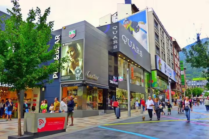 Vibrant shopping street in Andorra with luxury boutiques and bustling pedestrians, ideal for retail therapy on tour.