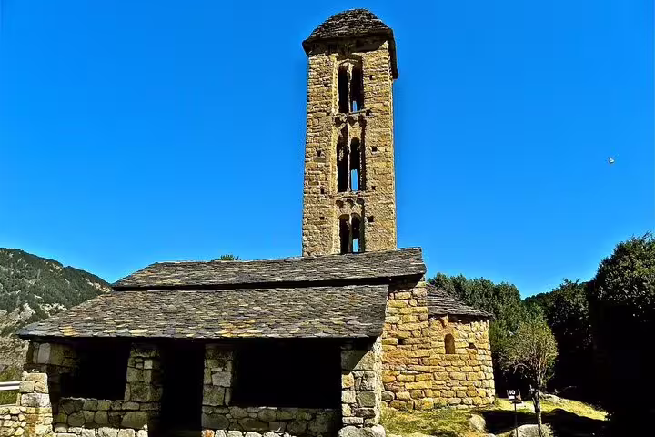Historic stone church with a tall bell tower under clear skies, showcasing Andorra's rich architectural heritage.