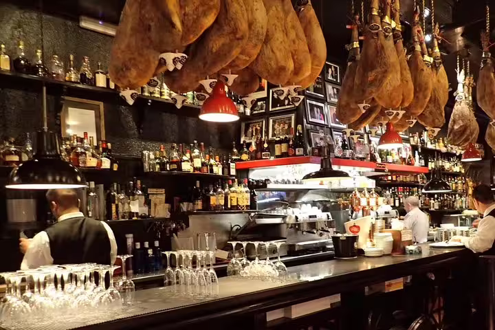 Cozy Andorran restaurant interior with hanging cured meats and a well-stocked bar, perfect for a traditional lunch experience.