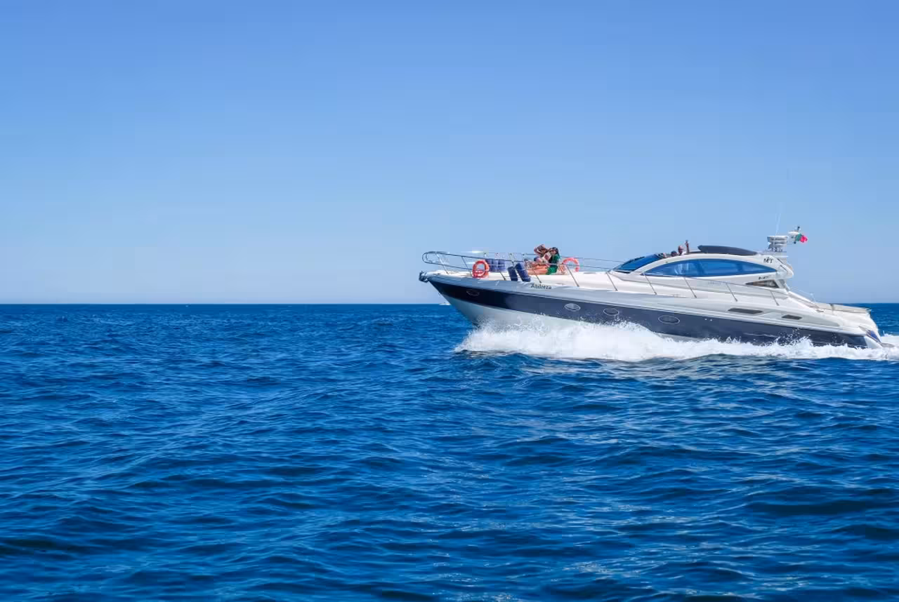 A sleek private luxury yacht cruising along the stunning blue waters of the Algarve coastline on a half-day boat tour