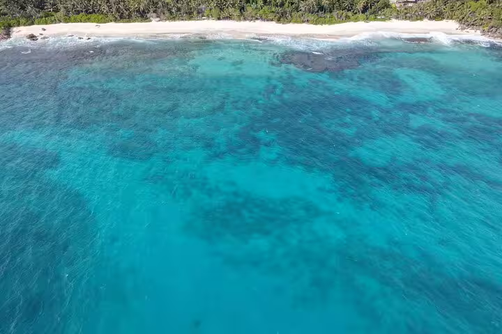 Aerial view of turquoise waters and sandy beach at Anse Major, perfect for snorkeling and relaxation.