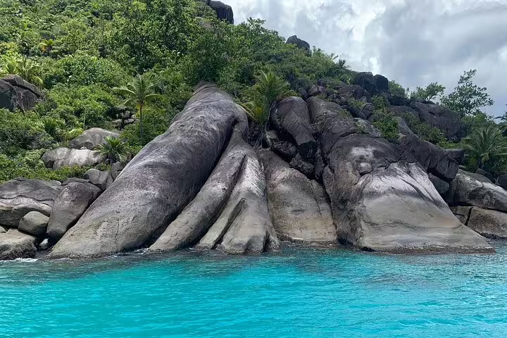 Scenic view of Anse Major's crystal-clear turquoise waters and lush green hills, ideal for snorkeling adventures.