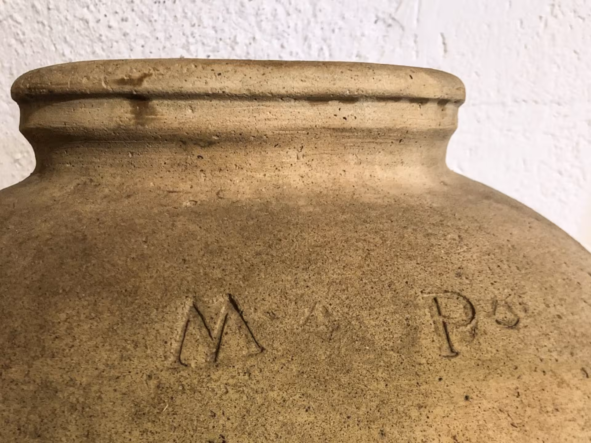 Close-up of an antique olive oil storage jar with engravings, featured in Perugia mill tours.