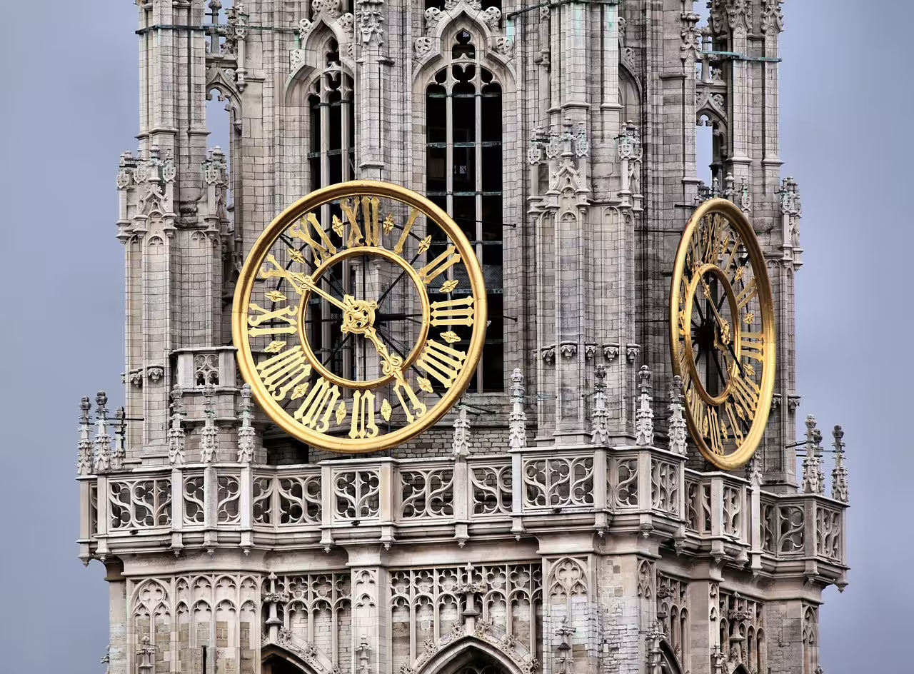 Gothic cathedral tower with ornate golden clock faces, a highlight of Antwerp's private walking tour in Belgium's historic heart.