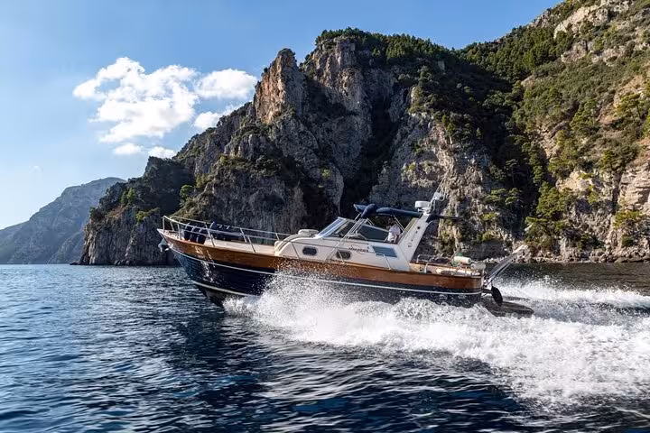 Apreamare 10 boat gliding through clear waters along the dramatic cliffs between Sorrento and Amalfi on a private tour.