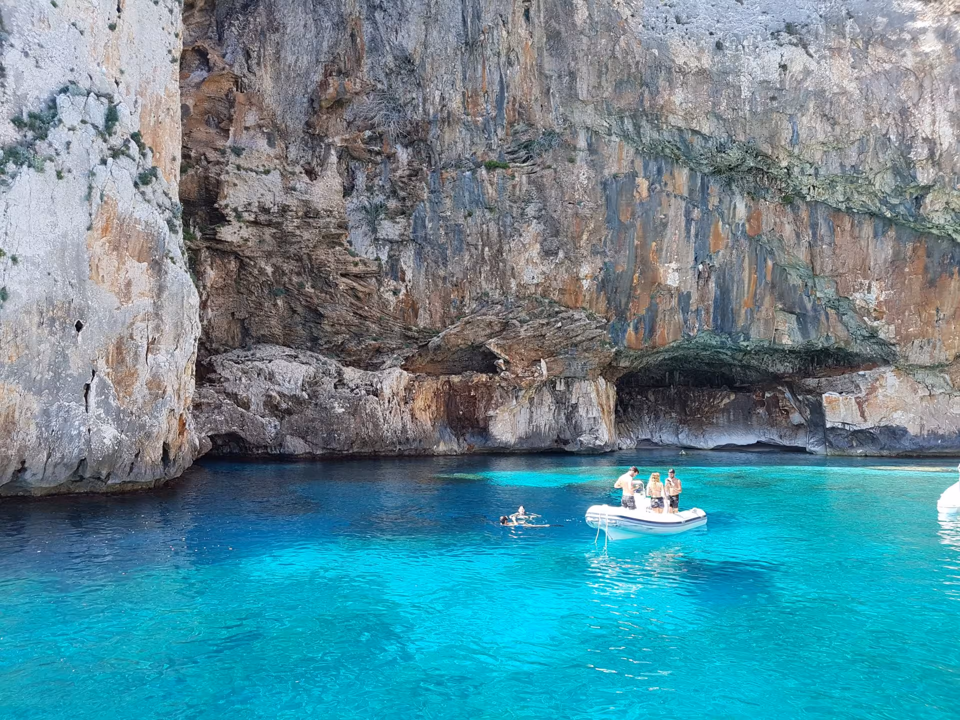 Sailing boat in crystal-clear waters near rugged cliffs in the Gulf of Orosei, perfect for a scenic Arbatax tour.