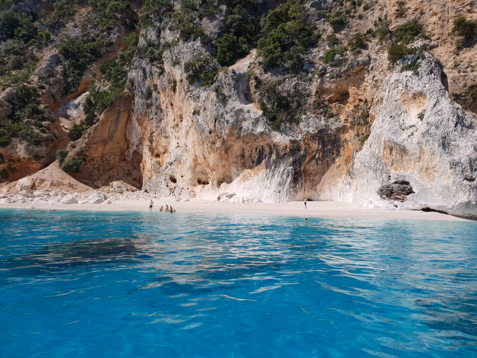 Pristine beach with turquoise waters and rugged cliffs in the Gulf of Orosei, perfect for sailing tours.
