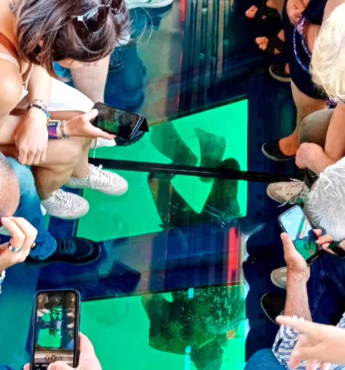 Guests photographing submerged ruins through glass-bottom boat on Archeoemotions Baia Sommersa tour