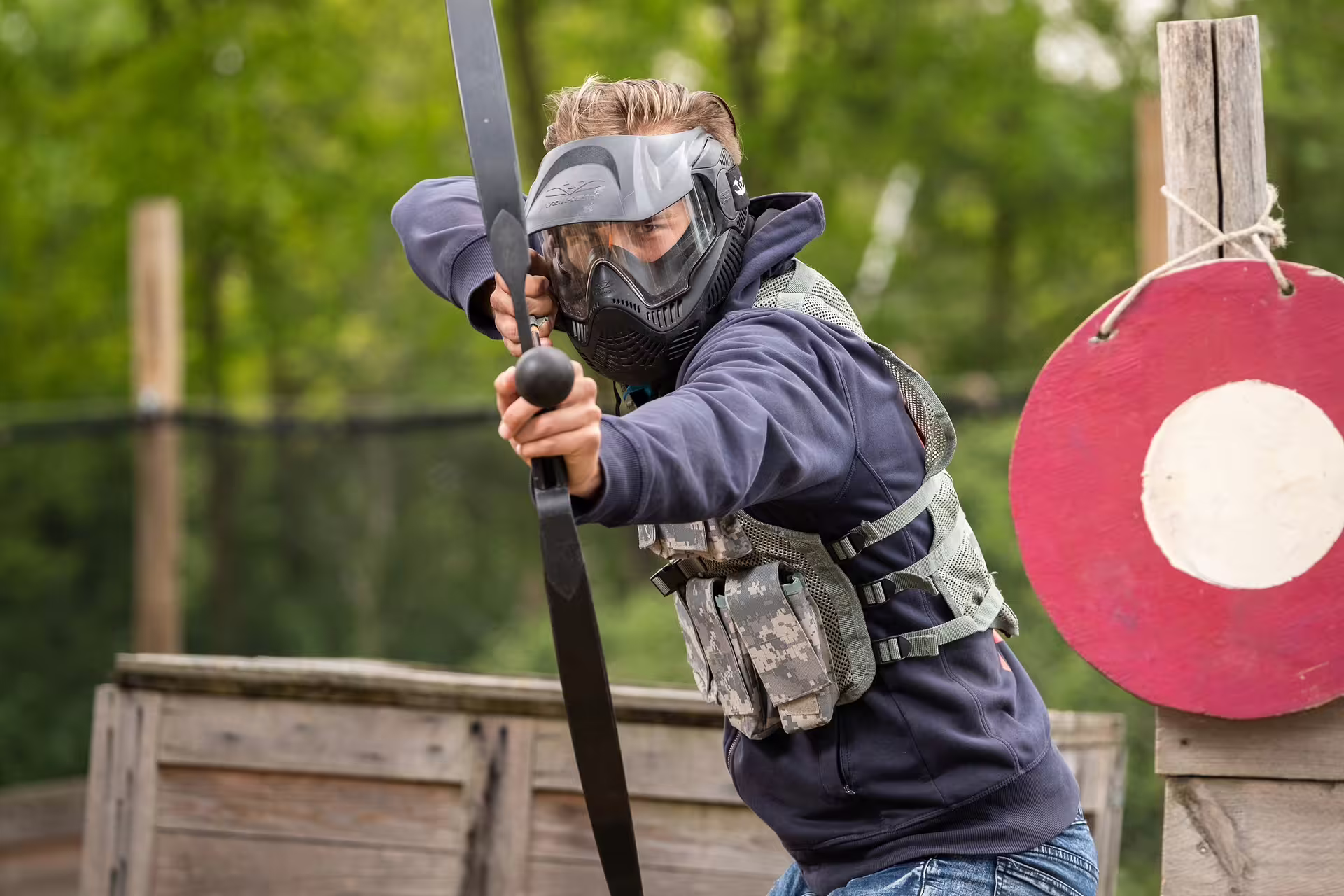 Player in protective mask aiming bow during Archery Tag in Weesp, Netherlands outdoor team battle game