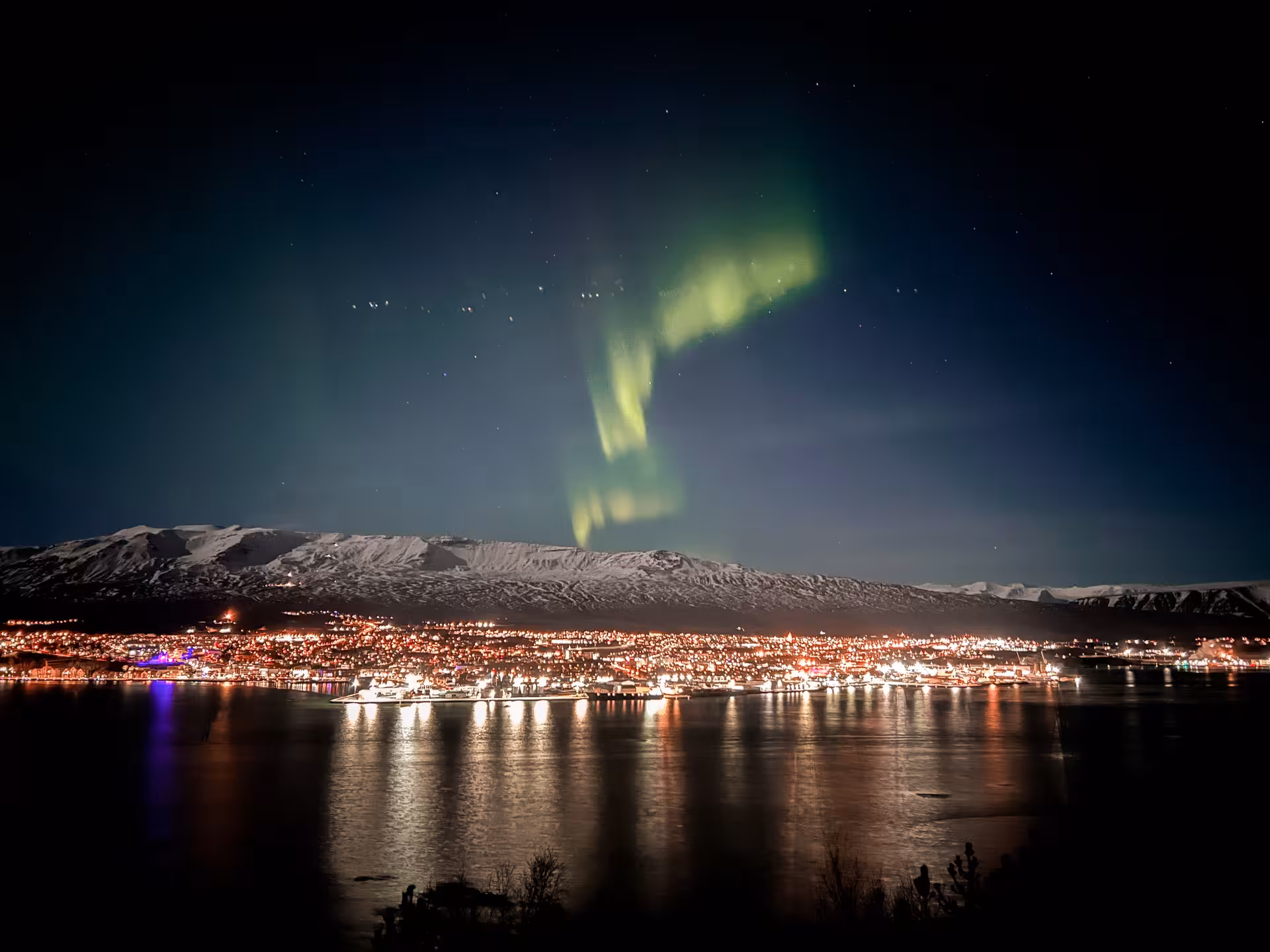 Northern Lights over Arctic fjord city and snowy mountains, ideal for private aurora odyssey tour