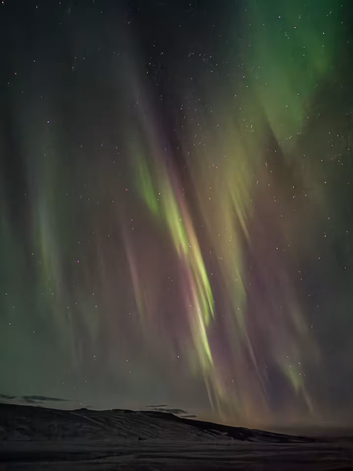 Dancing green and purple Northern Lights above Arctic tundra at night on Adventure Arctic Odyssey aurora tour