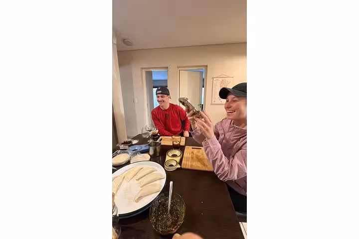 Two people joyfully preparing Argentinian dishes with fresh ingredients at a cozy cooking class table setting.