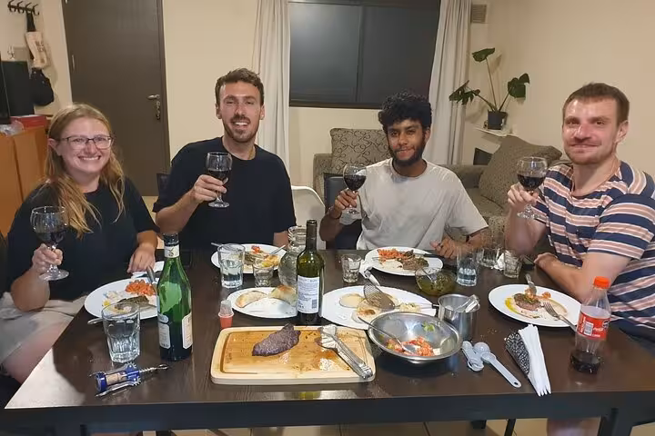 Group of friends enjoying homemade Argentinian cuisine and wine at a lively dining table, celebrating culinary traditions.
