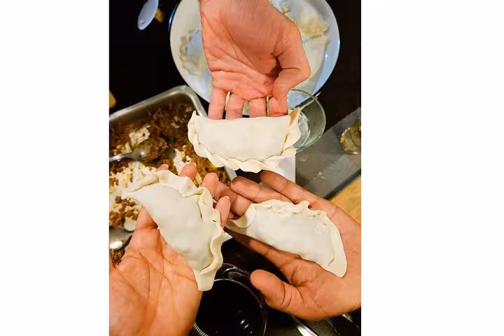 Hands showcasing homemade Argentinian empanadas ready to be cooked, highlighting authentic culinary experiences.