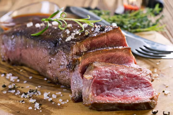 Delicious medium-rare Argentinian steak garnished with sea salt on a wooden cutting board, perfect for culinary adventures.