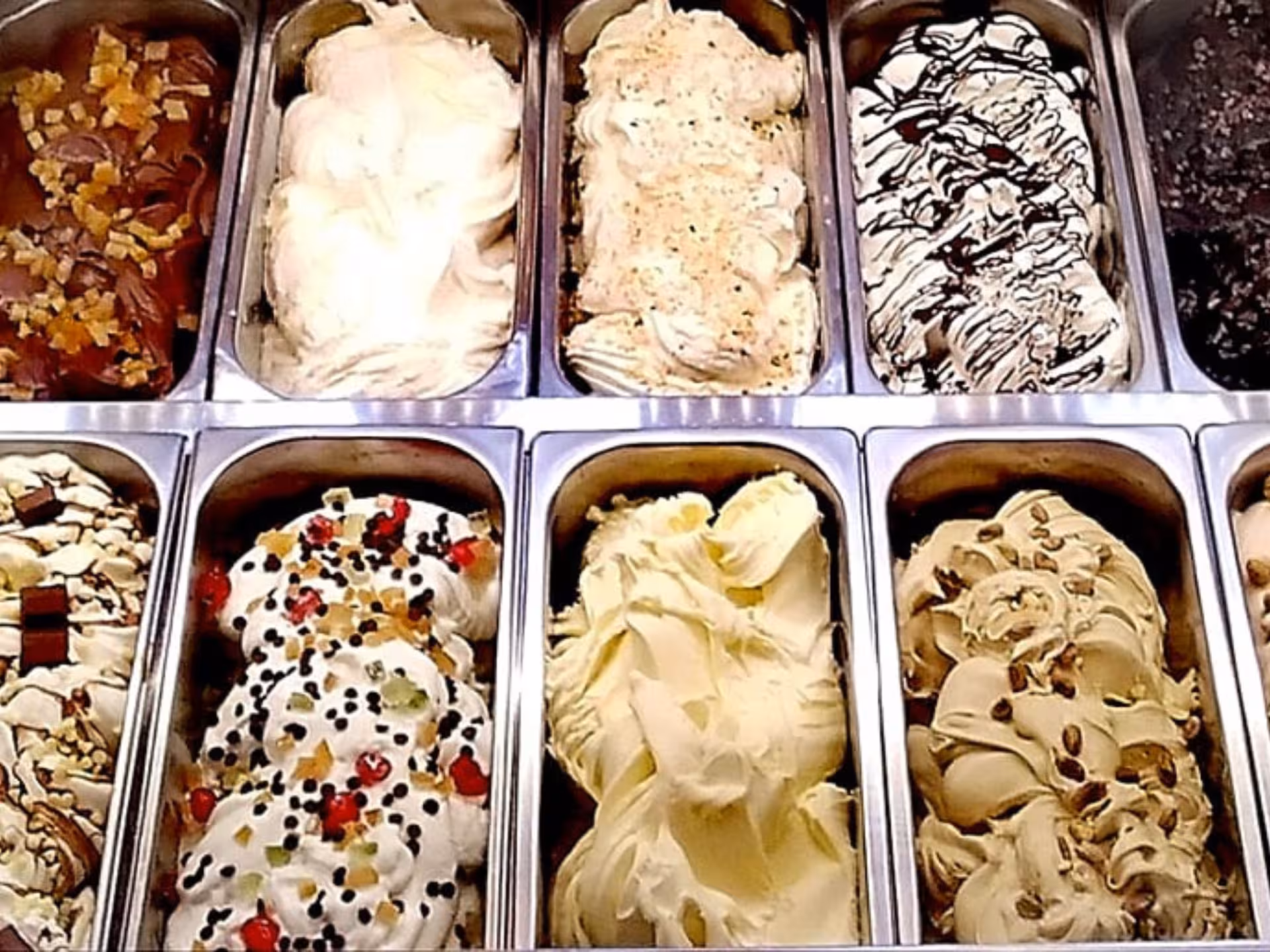 Variety of artisanal gelato flavors on display at a Perugia chocolate factory tasting experience.
