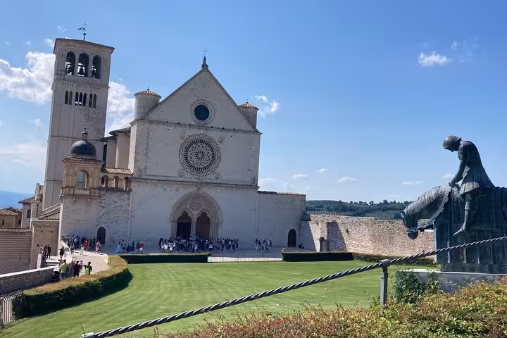 Visit Assisi's Basilica of Saint Francis with its iconic rose window and statue, a highlight of the Rome to Assisi private tour.