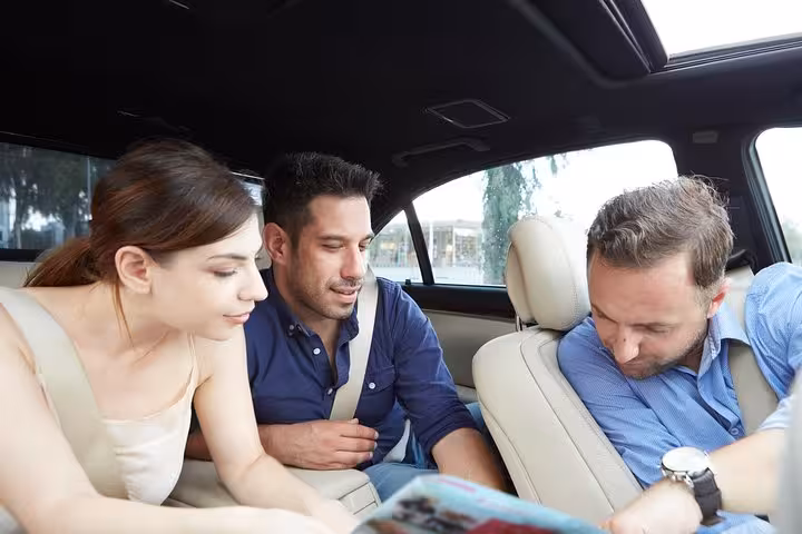 Inside private car after Athens airport pickup, driver explains city highlights during 1-hour welcome orientation tour