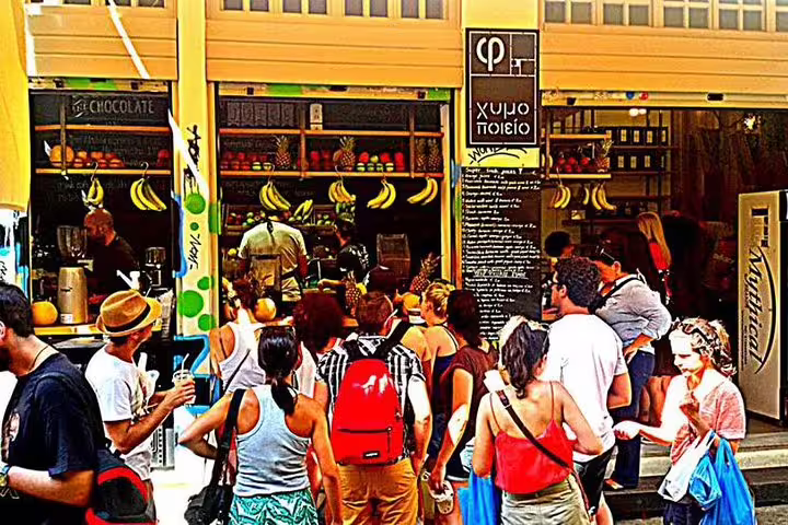 Small-group Athens food tour stop at a busy juice bar in Central Market, tasting fresh Greek produce