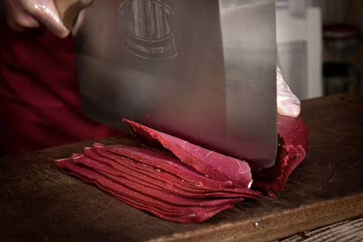Close-up of cured meat being sliced for tastings on an Athens gourmet food small group walking tour