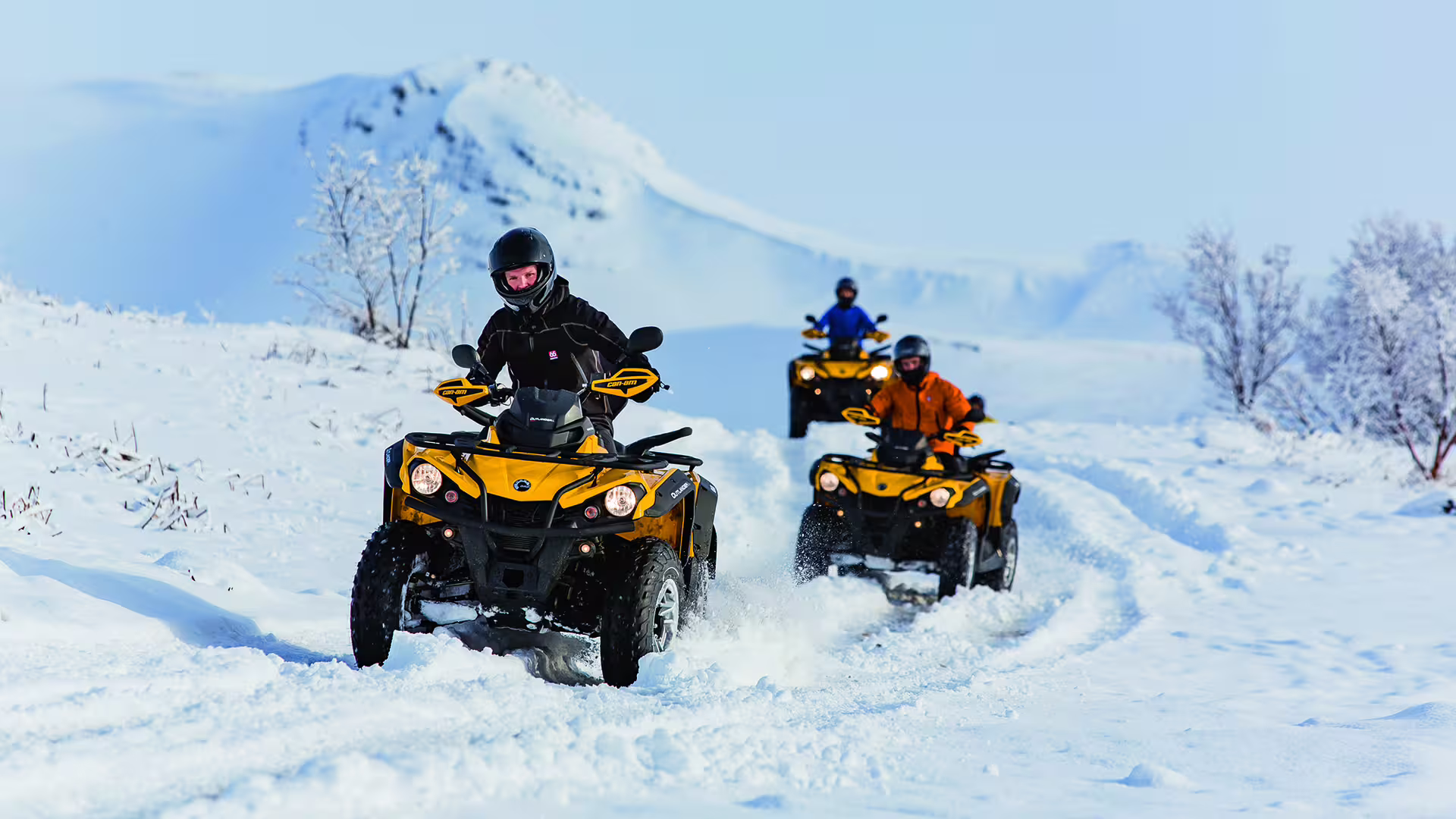 Riders enjoy an exhilarating ATV adventure through snowy terrain with scenic mountain views, perfect for an ATV and helicopter tour.