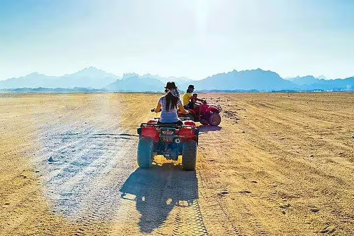 Riders on ATV quad bikes crossing Hurghada desert with mountain views on safari adventure tour