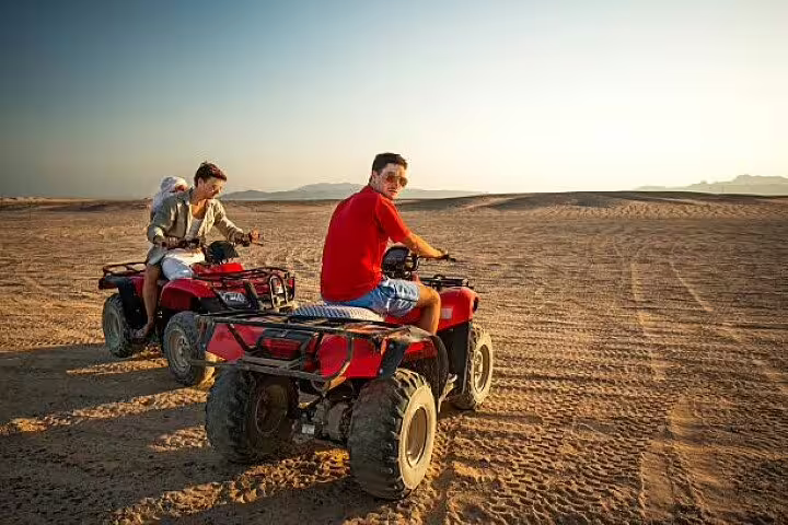Riders on red ATV quad bikes in Hurghada desert safari, off-road adventure tour with optional camel ride experience